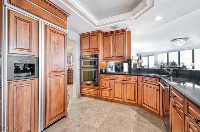 kitchen featuring sink, dishwasher, a raised ceiling, ornamental molding, and dark stone counters