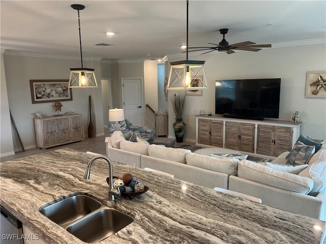 kitchen featuring stone counters, sink, ornamental molding, pendant lighting, and ceiling fan