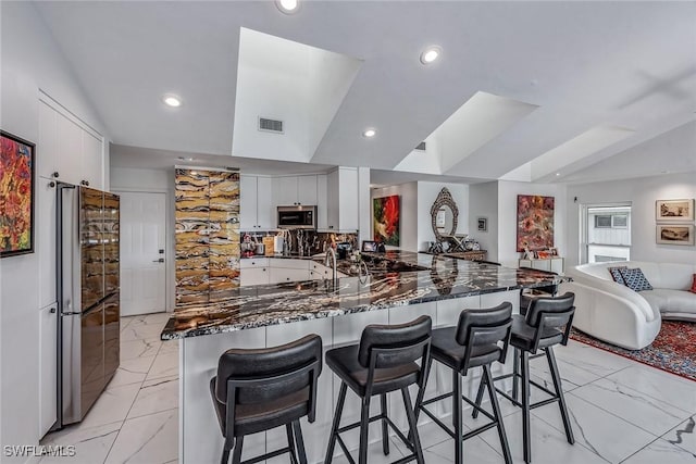 kitchen featuring white cabinets, stainless steel appliances, a kitchen bar, and kitchen peninsula