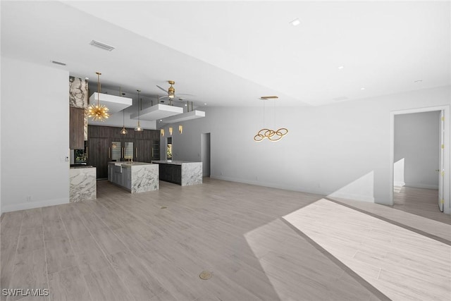 living room featuring light wood-type flooring and ceiling fan with notable chandelier