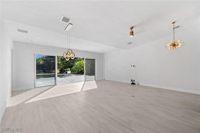 unfurnished living room with ceiling fan with notable chandelier and light hardwood / wood-style flooring