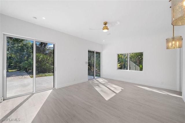 unfurnished room with ceiling fan, light wood-type flooring, and a wealth of natural light