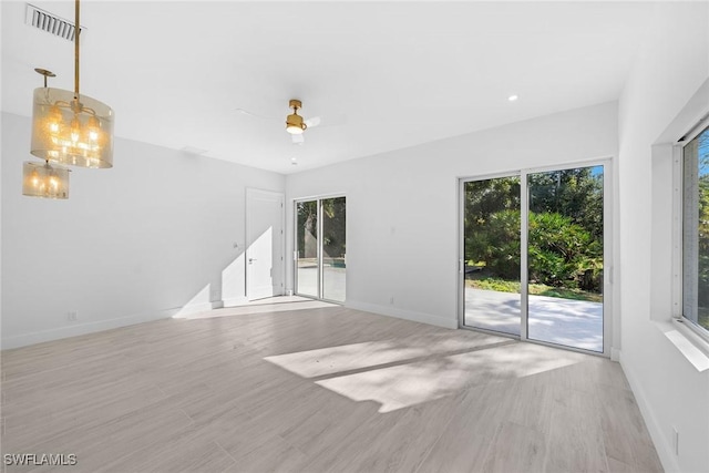 unfurnished living room with light hardwood / wood-style floors and ceiling fan with notable chandelier