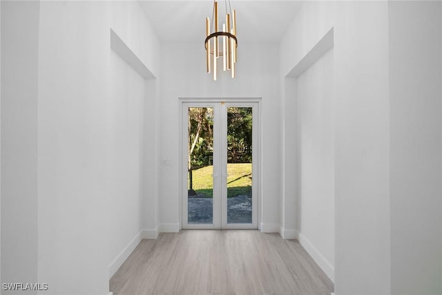 doorway featuring french doors, light hardwood / wood-style flooring, and an inviting chandelier