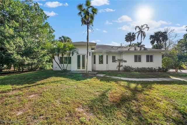 rear view of property featuring a lawn and french doors