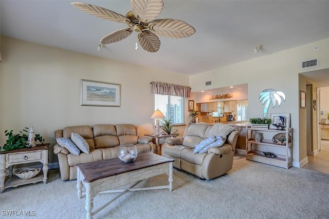 carpeted living room featuring ceiling fan and sink