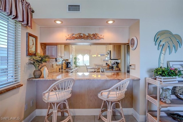 kitchen with kitchen peninsula, light stone countertops, and a breakfast bar