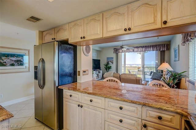 kitchen featuring light stone countertops, stainless steel refrigerator with ice dispenser, and light tile patterned floors