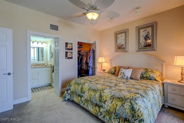 carpeted bedroom with a closet, connected bathroom, ceiling fan, and a spacious closet