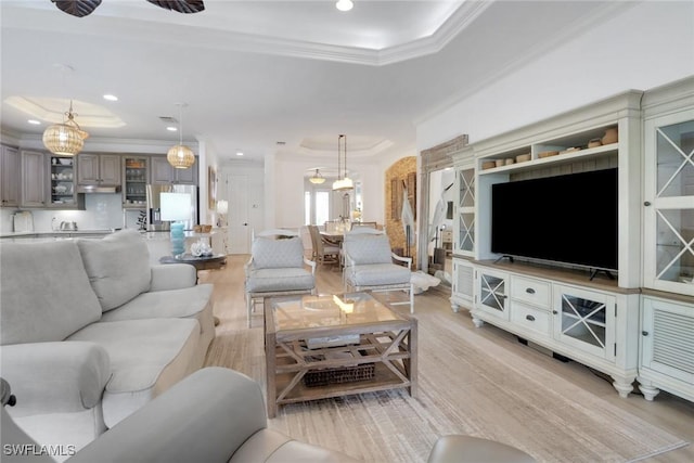 living room featuring a raised ceiling, ceiling fan, light hardwood / wood-style floors, and crown molding