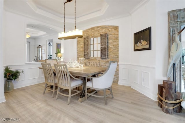 dining room with ornamental molding, a tray ceiling, and light hardwood / wood-style floors