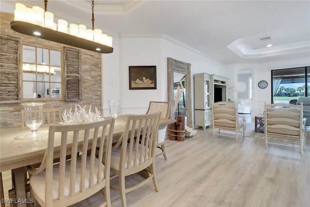 dining area with ornamental molding, a tray ceiling, and hardwood / wood-style flooring