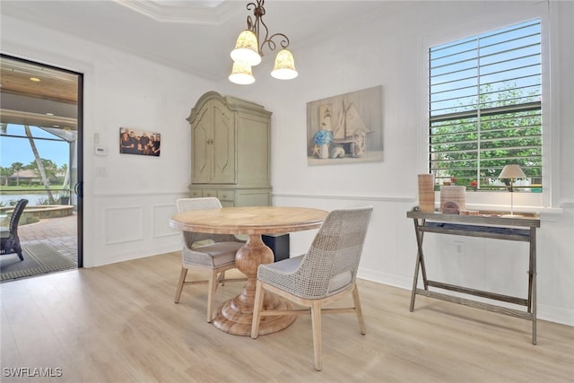 dining area featuring light wood-type flooring, crown molding, and a notable chandelier