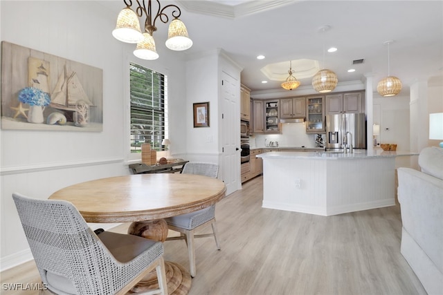 dining space with light hardwood / wood-style floors, a notable chandelier, crown molding, and sink