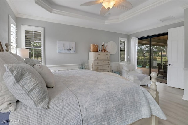 bedroom featuring ceiling fan, access to outside, crown molding, and a tray ceiling