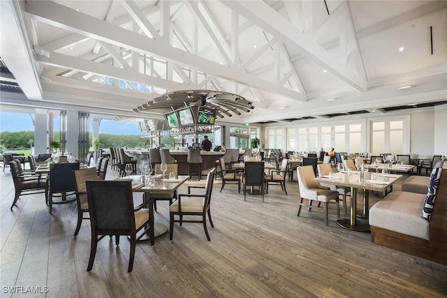 dining space with high vaulted ceiling, beamed ceiling, and hardwood / wood-style flooring