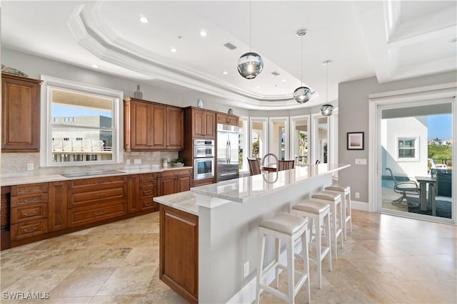 kitchen with a center island, decorative light fixtures, stainless steel appliances, decorative backsplash, and light stone counters