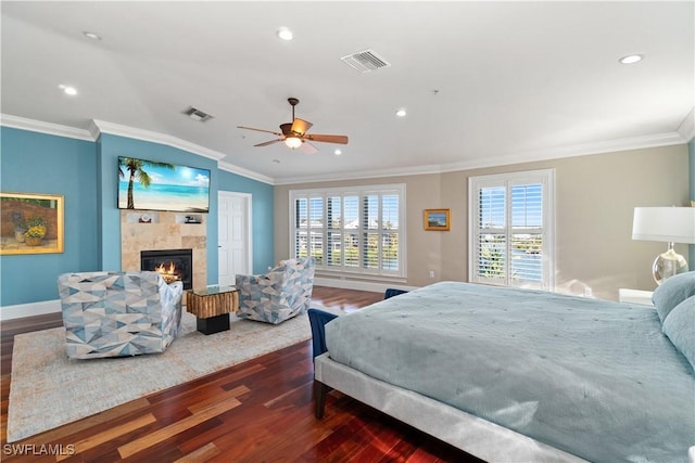 bedroom featuring ceiling fan, crown molding, dark hardwood / wood-style floors, and a tile fireplace