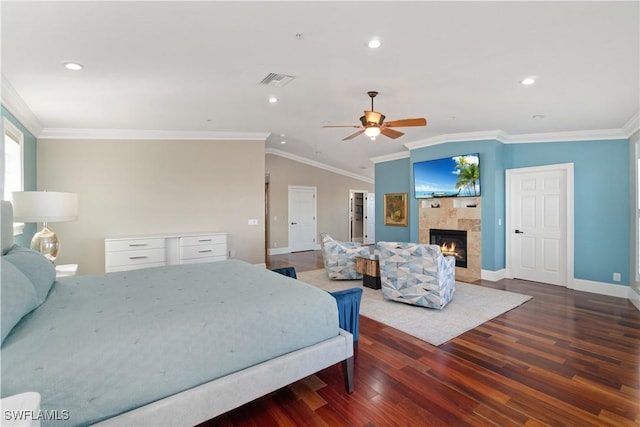 bedroom featuring dark wood-type flooring, ornamental molding, vaulted ceiling, ceiling fan, and a tile fireplace