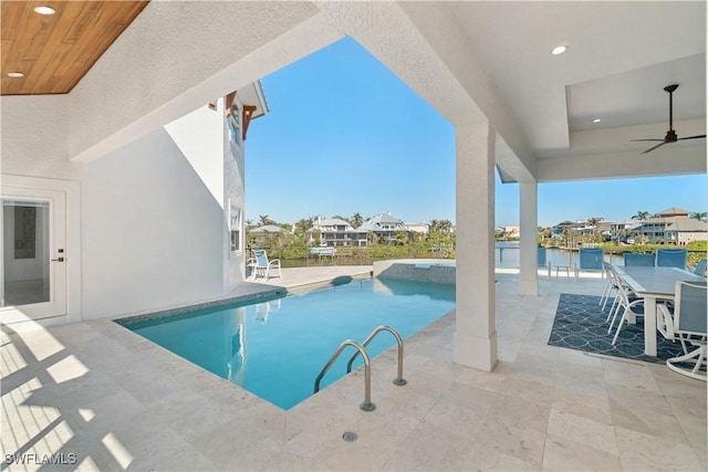 view of pool with ceiling fan, a water view, and a patio