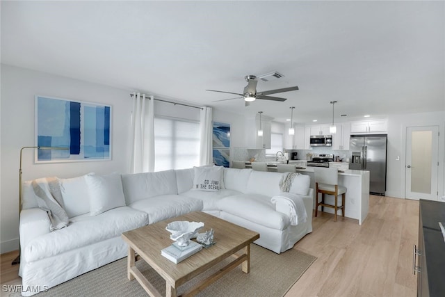 living room featuring light hardwood / wood-style flooring and ceiling fan