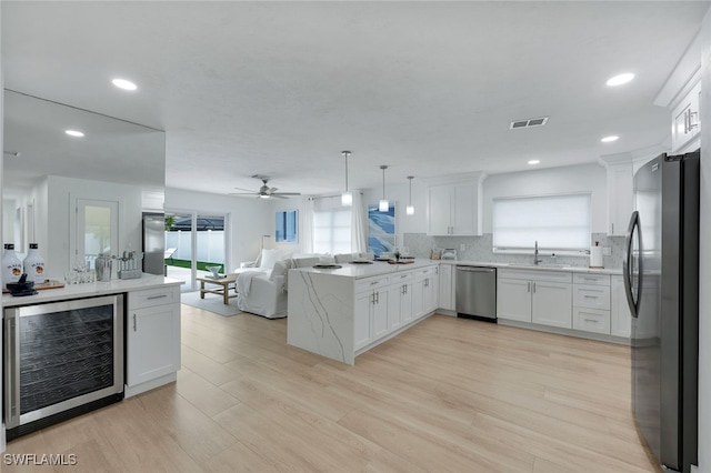 kitchen featuring pendant lighting, white cabinets, stainless steel appliances, wine cooler, and kitchen peninsula