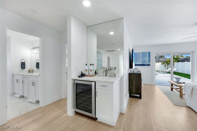 bar featuring white cabinetry, sink, light hardwood / wood-style flooring, light stone counters, and wine cooler