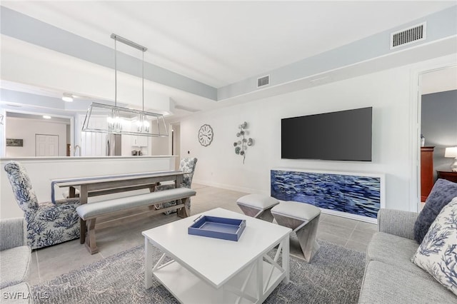 living room featuring light tile patterned floors, a chandelier, visible vents, and baseboards