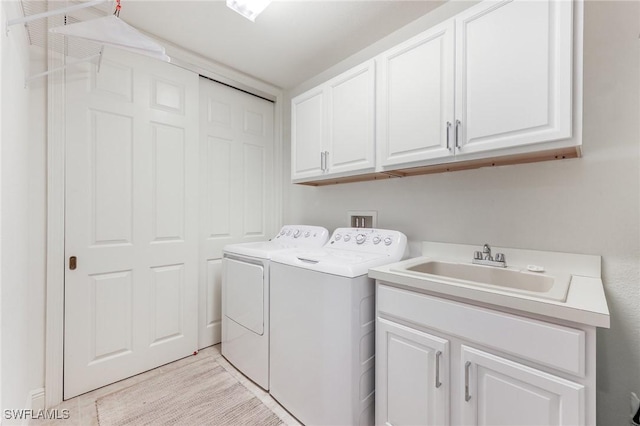 laundry area with washer and clothes dryer, a sink, and cabinet space