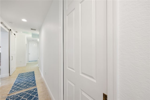 corridor with a barn door, visible vents, baseboards, and recessed lighting