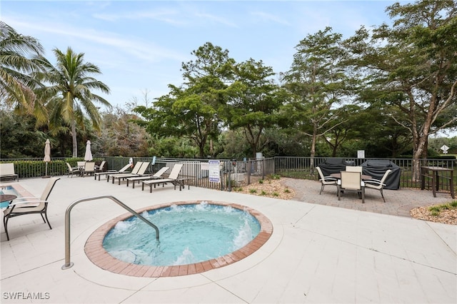 view of swimming pool featuring a community hot tub, a grill, a patio, and fence