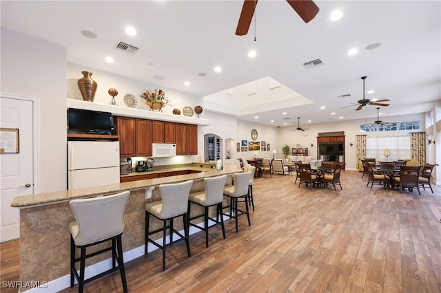 kitchen with light wood-style floors, white appliances, visible vents, and a ceiling fan