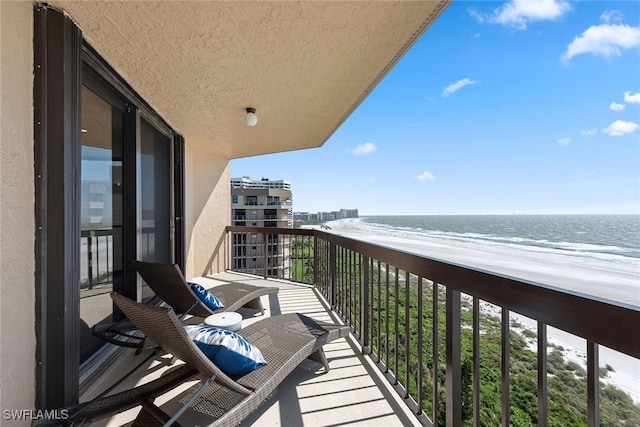 balcony featuring a beach view and a water view