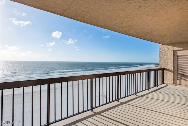 balcony featuring a water view and a beach view