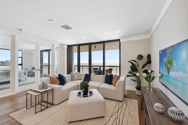 living room featuring floor to ceiling windows, crown molding, and light hardwood / wood-style flooring