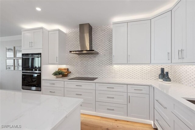 kitchen with decorative backsplash, white cabinetry, and wall chimney exhaust hood