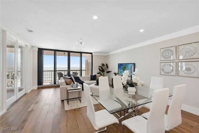 dining room featuring french doors, light hardwood / wood-style flooring, expansive windows, and crown molding