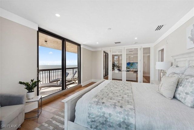 bedroom featuring floor to ceiling windows, wood-type flooring, access to outside, a water view, and ornamental molding