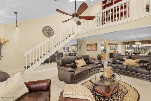 living room with ceiling fan with notable chandelier, a high ceiling, and carpet flooring