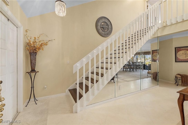 stairway with tile patterned floors and an inviting chandelier