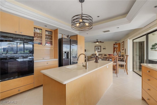 kitchen featuring decorative light fixtures, an island with sink, ceiling fan with notable chandelier, stainless steel refrigerator with ice dispenser, and a tray ceiling