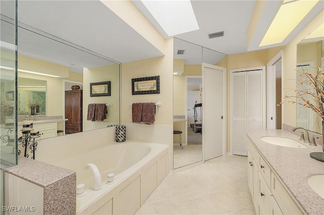 bathroom with vanity, tile patterned floors, a skylight, and a bathing tub