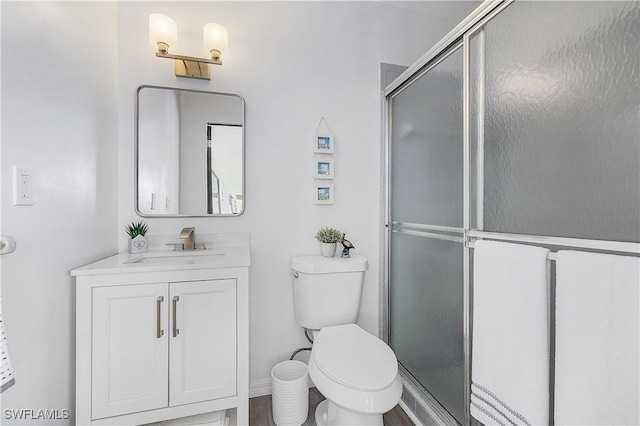 bathroom featuring toilet, a shower with shower door, and vanity