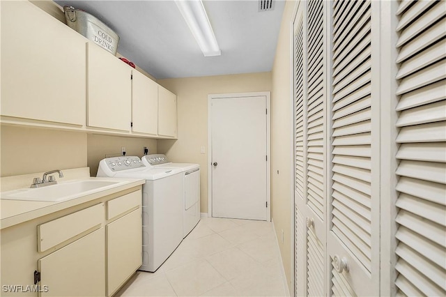 laundry area featuring sink, washing machine and dryer, light tile patterned floors, and cabinets