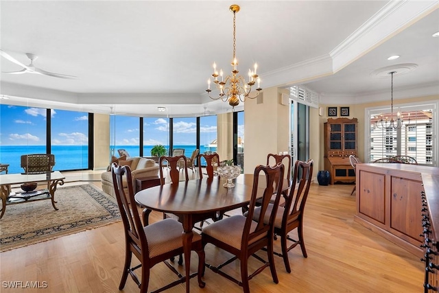 dining room featuring a water view, ornamental molding, ceiling fan with notable chandelier, and light wood-type flooring