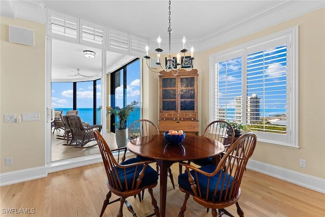 dining room with ornamental molding, ceiling fan with notable chandelier, a water view, and light hardwood / wood-style floors