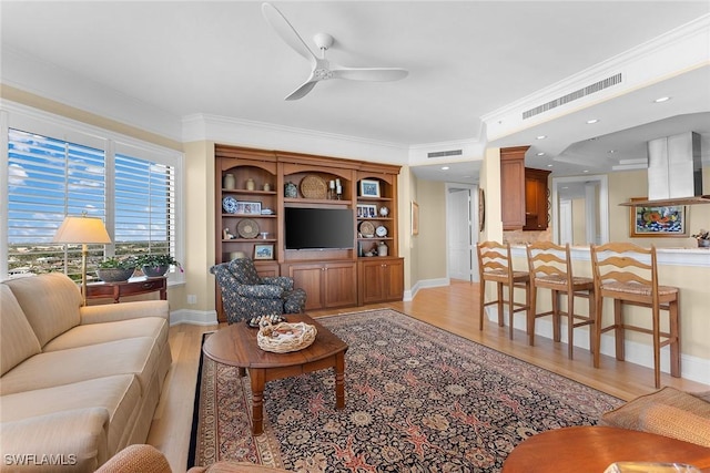 living room featuring ceiling fan, light wood-type flooring, and crown molding