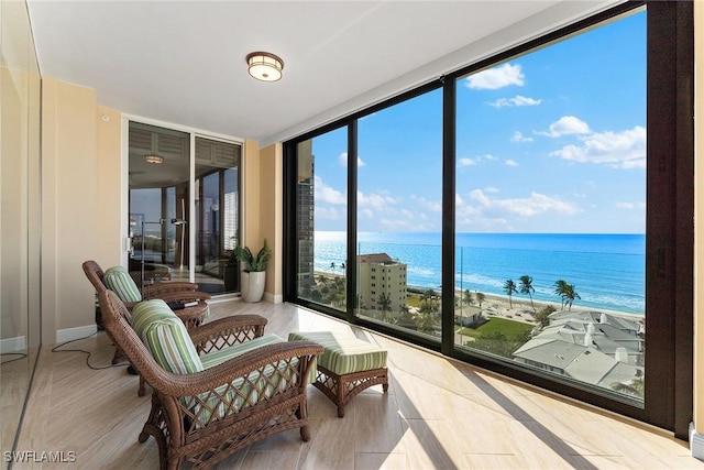 sunroom / solarium featuring a water view and a beach view