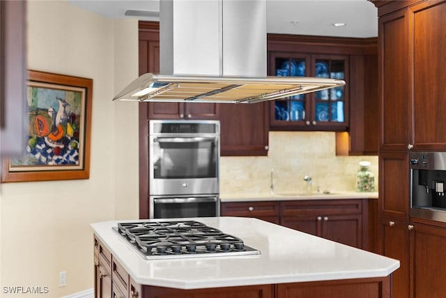 kitchen featuring island exhaust hood, appliances with stainless steel finishes, decorative backsplash, sink, and a kitchen island