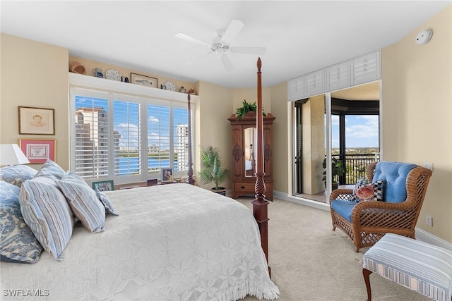 bedroom with access to exterior, ceiling fan, a water view, and multiple windows